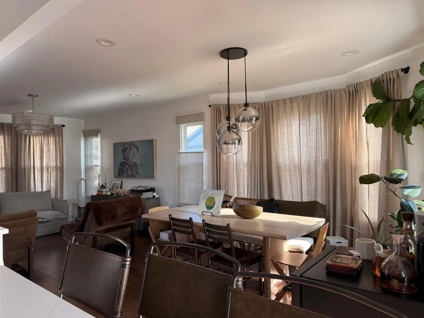 A sunlit dining room with linen curtains and a long oak table